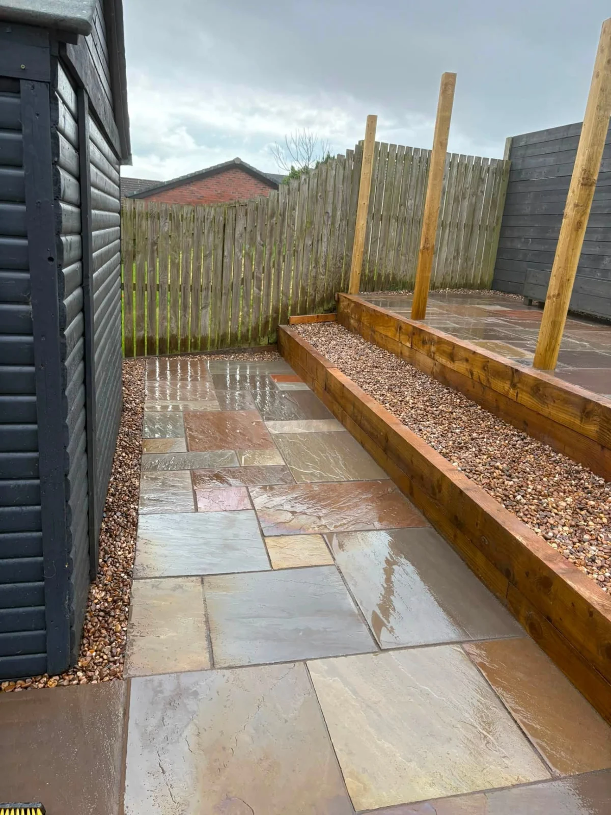Sandstone garden pathway alongside raised timber sleeper borders and gravel