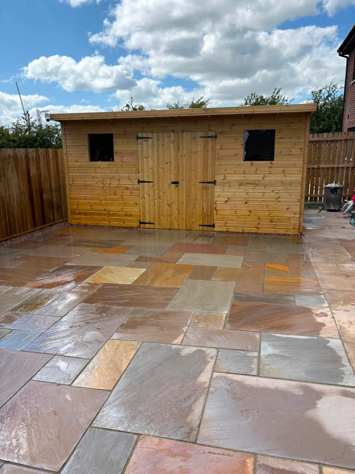 Timber garden building surrounded by a finished sandstone patio